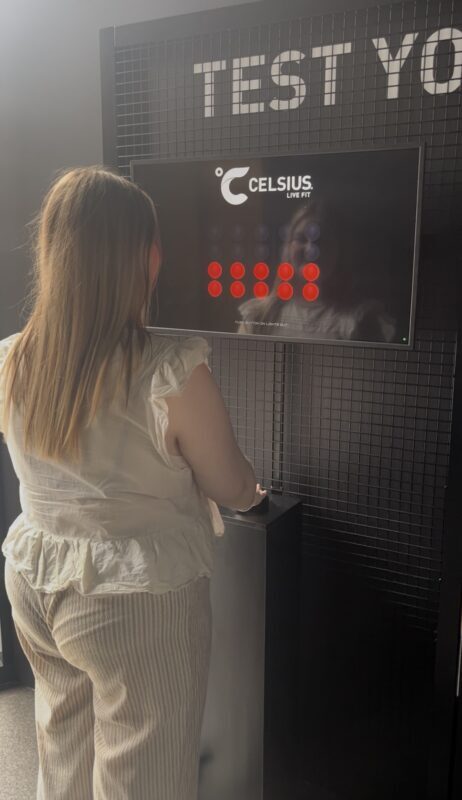 A woman tests her reaction time at a Celsius-branded interactive display